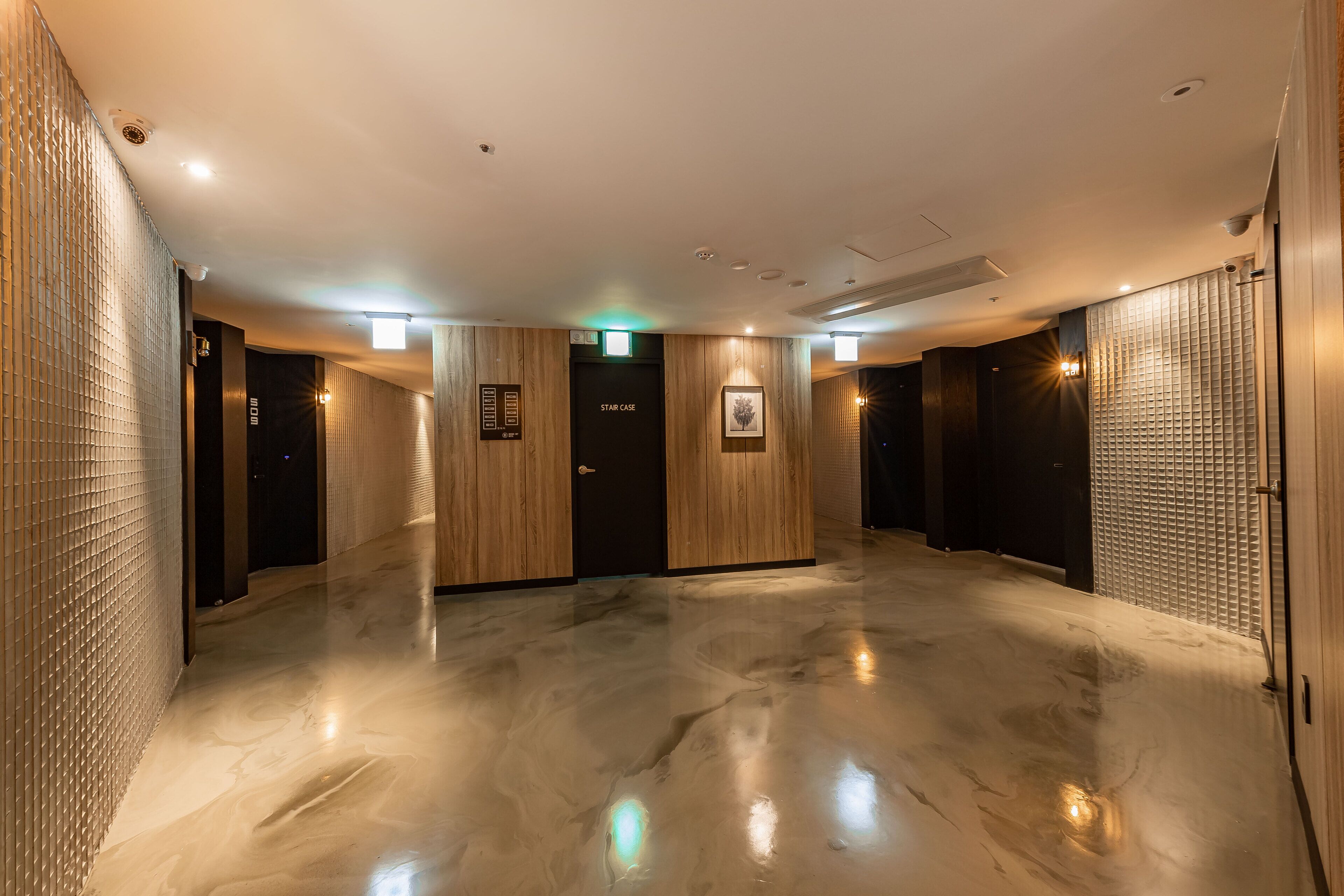 Um lobby espaçoso e moderno, com piso lustroso, painéis de madeira e um elevador Star Case.