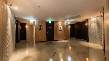 A spacious, modern lobby with a polished floor, wooden panel walls, and a Star Case elevator.