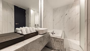 Un baño moderno con tocador de mármol, un espejo grande, una bañera y una puerta oscura.