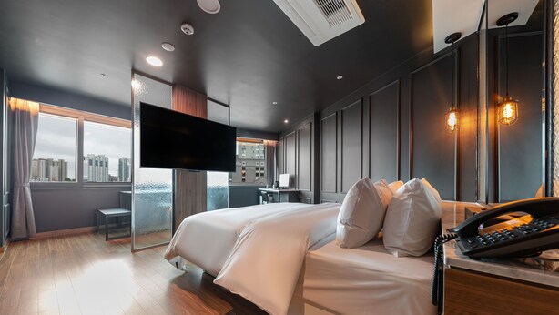 A modern hotel room with a large bed, a desk, a flat-screen TV, and a city view. - Seosan Browndot Hotel (Seosan)