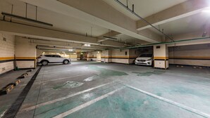 A multi-level parking garage with several cars parked, concrete floors, and overhead pipes. - Seosan Browndot Hotel (Seosan)