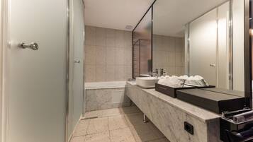Un baño moderno con tocador de mármol, bañera y un espejo grande.
