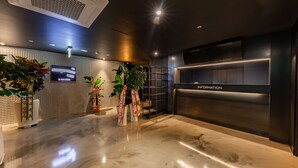 A modern reception area with a marble floor, potted plants, a flat-screen TV, and a 'Welcome' sign. - Seosan Browndot Hotel (Seosan)