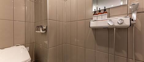 Un baño moderno con inodoro, ducha y espejo.
