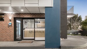 A modern hotel entrance with a reception desk, a phone, and a sign that reads "Avenue Motel Apartments." - Avenue Motel Apartments (South Toowoomba)