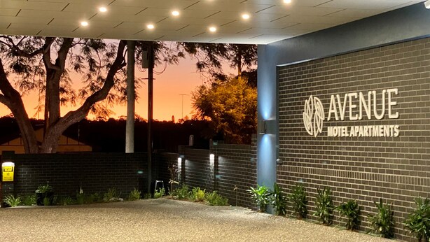 A brick building with a sign reading "AVENUE MOTEL APARTMENTS" and a covered entrance area with a gravel driveway. - Avenue Motel Apartments (South Toowoomba)
