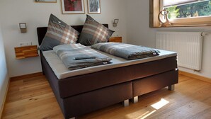 A modern bedroom with a bed, wooden floor, and artwork on the wall.
