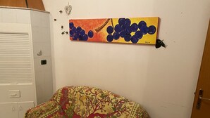 Une pièce avec un canapé à motifs, un tableau accroché au mur et un meuble blanc.