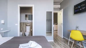 A modern hotel room with a bed, a desk, a chair, a TV, and a bathroom with a mirror and sink. - albinariobrescia  (Brescia)