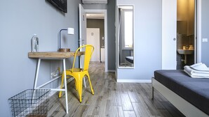 A compact bedroom with a bed, a desk, and a chair. There is a bathroom visible through an open door. - albinariobrescia  (Brescia)