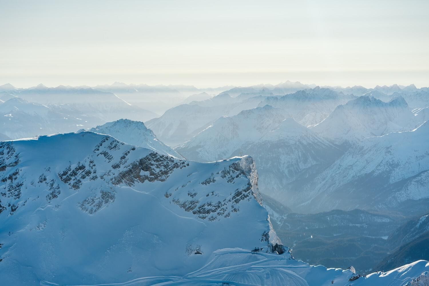 A panoramic view of snow-covered mountain peaks with a clear sky.