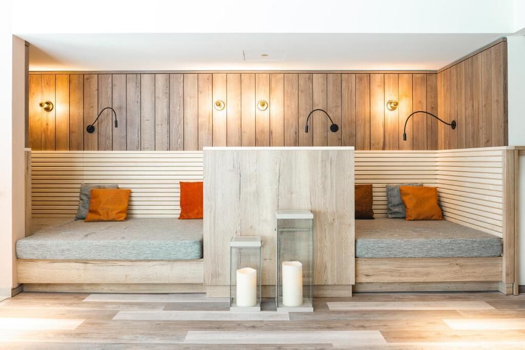 A modern interior with two seating areas, wooden panel walls, and wall-mounted lighting.