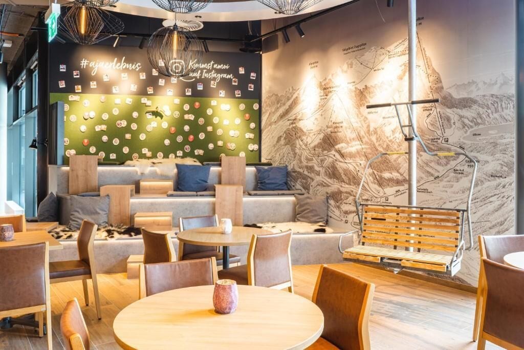 Un espacio lounge moderno con asientos, mesas y una pared decorada con un mapa y arte para Instagram.