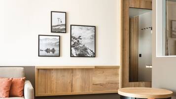 A modern living room with a sofa, a round wooden table, and framed artwork on the wall.