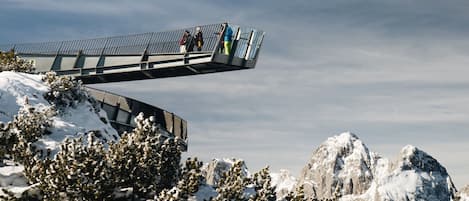 Une montagne enneigée, avec un pont piétonnier et des pics rocheux en arrière-plan.