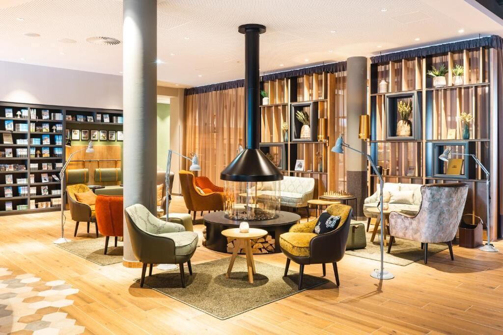 A modern lounge area with a fireplace, comfortable seating, and a bookshelf.