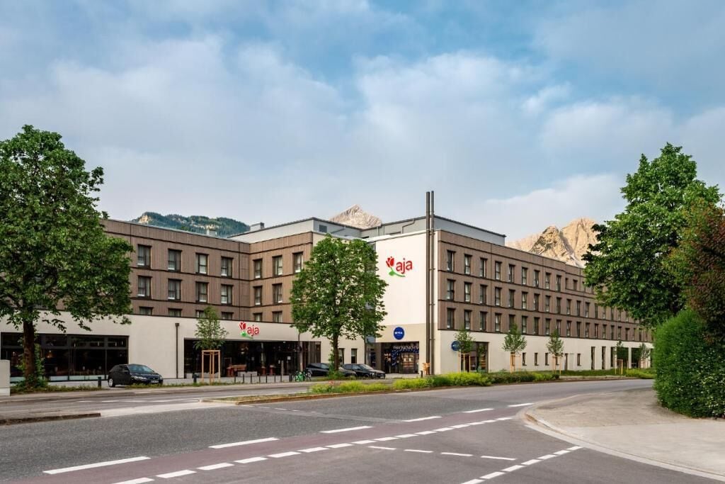 A modern hotel with a flat roof, multiple windows, and a prominent logo.