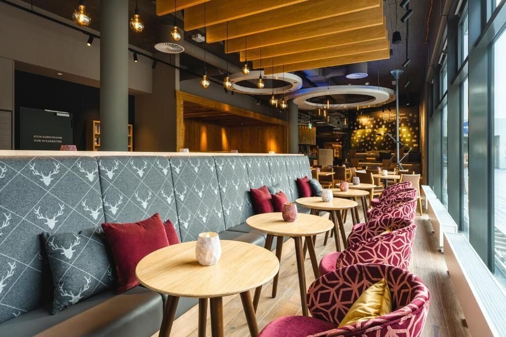 A modern interior with a seating area featuring round tables and cushioned seating.