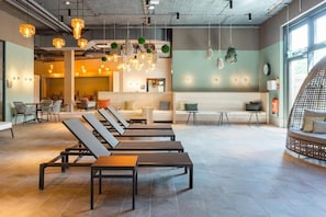 A modern lounge area with sun loungers, a reception desk, and hanging lights. - aja Garmisch-Partenkirchen (Garmisch-Partenkirchen)