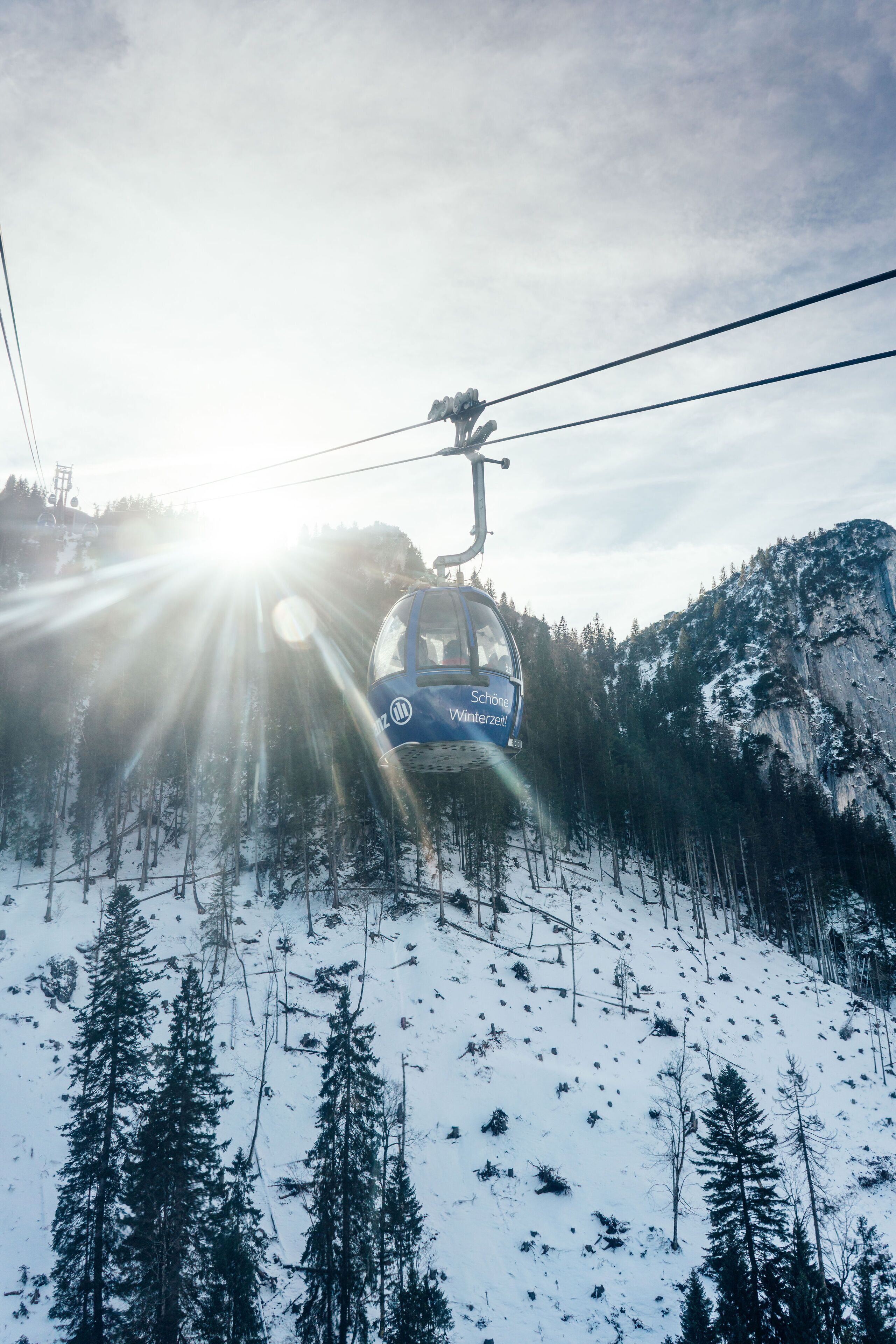 A cable car ascending a snowy mountain with a clear sky.