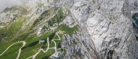 Een bergachtig landschap met een kronkelend pad, een klein gebouw en een brug.
