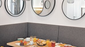 A breakfast setup with a table, chairs, and a variety of food and drinks. - Stadthotel Oberndorf - 24h Self Check-In Terminal  (Oberndorf bei Salzburg)