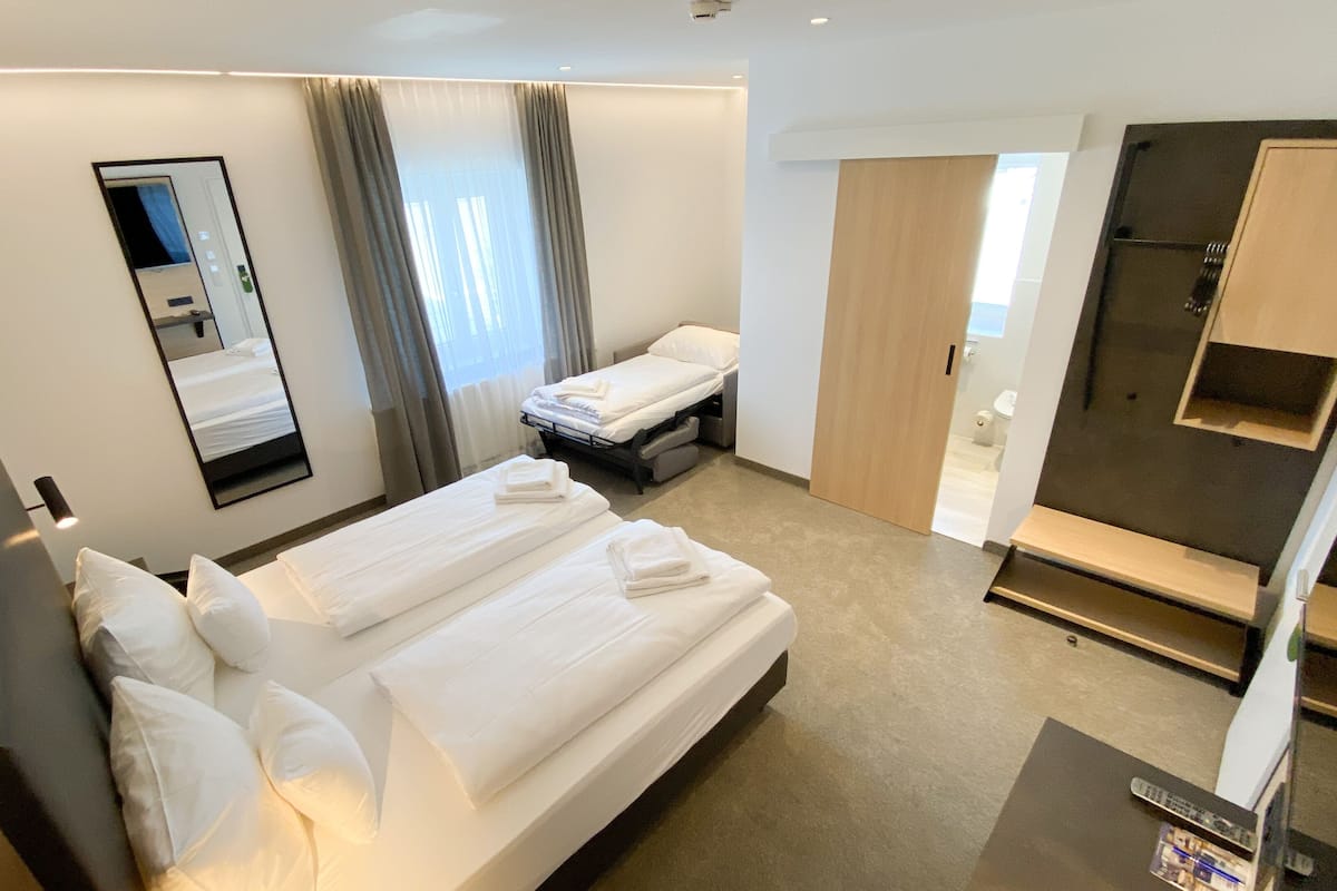 Ett hotellrum med två sängar, en stor spegel, en garderob och en tv.