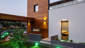 A modern building with a wooden facade, a glass balcony, and outdoor lighting. - Sauna, heated pool, kids pool, close to the beach & shops! (Rethymno)
