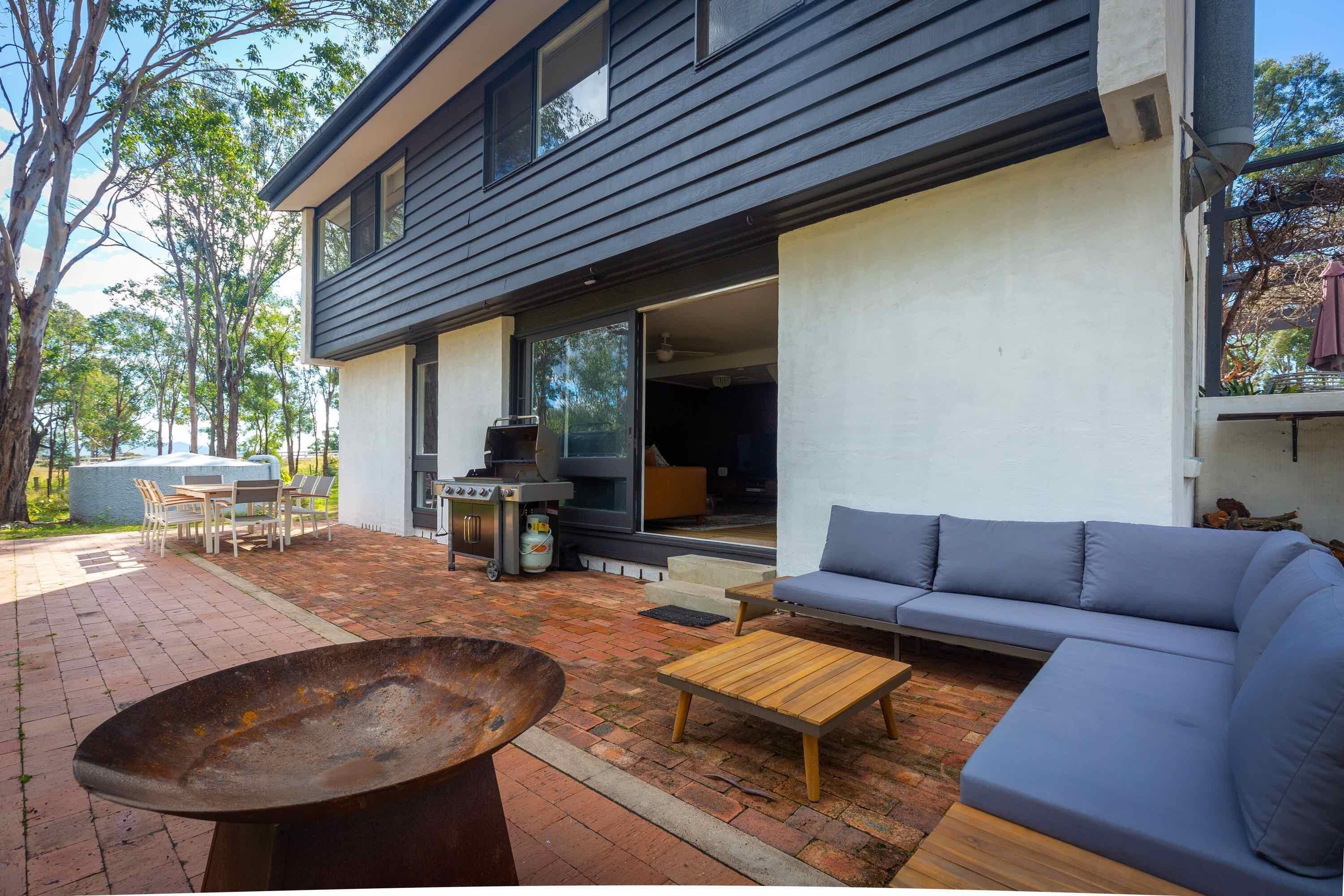 A modern outdoor patio with a barbecue grill, a wooden table, and a blue sofa.