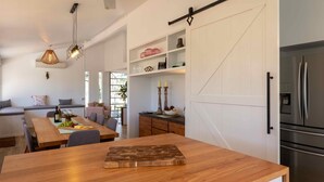 A modern kitchen with a wooden dining table, a built-in oven, and a stainless steel refrigerator. - Marlu Station - Secluded family getaway in Broke (Broke)