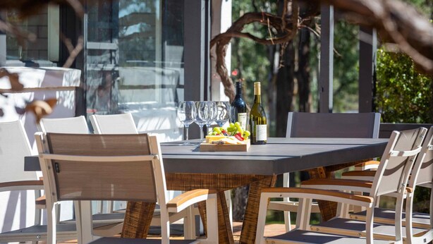 An outdoor dining area with a table set for four, surrounded by white chairs with wooden accents. - Marlu Station - Secluded family getaway in Broke (Broke)