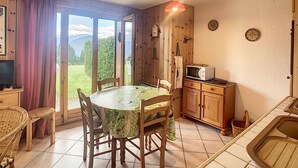 Ein Essbereich mit Tisch, Stühlen, einer Mikrowelle und Blick ins Freie.