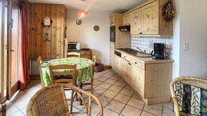 Eine kleine Küche mit Holzausstattung, einem Esstisch mit Stühlen, einer Mikrowelle und einer Kaffeemaschine.