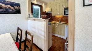 Eine kleine Küche mit Holzausstattung, einem eingebauten Backofen und einem Fenster mit Blick auf eine verschneite Landschaft.