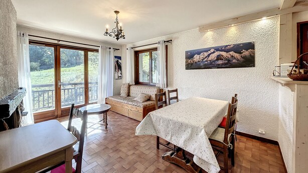 Ein gemütlicher Essbereich mit einem Holztisch und Stühlen, einer gepolsterten Bank und einem Bild an der Wand.