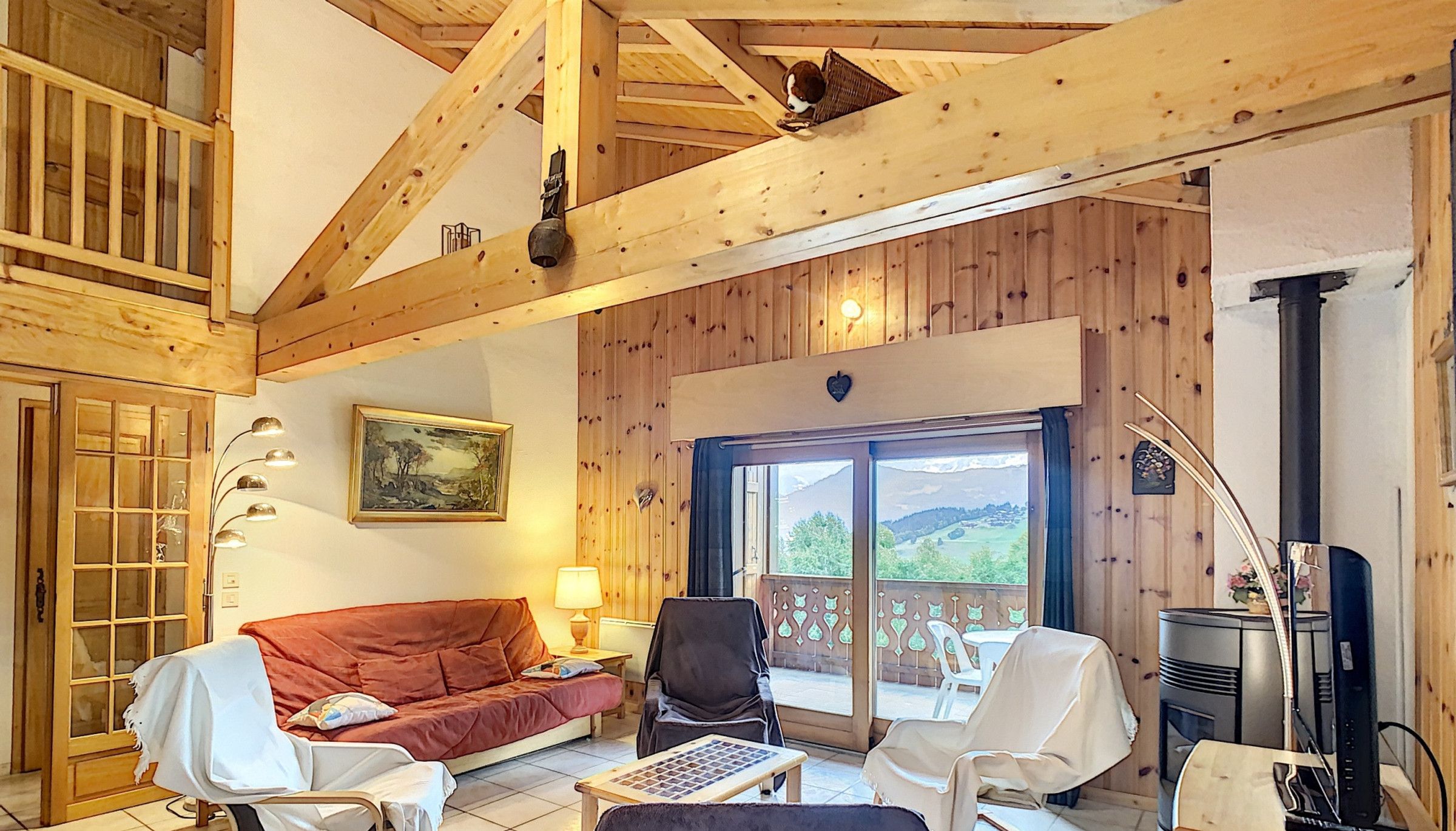 A cozy living room with a wooden ceiling, a sofa, a table, and a fireplace.