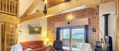 A cozy living room with a wooden ceiling, a sofa, a table, and a fireplace.