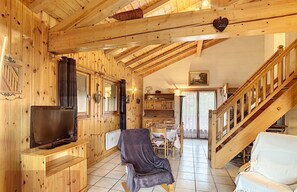 A wooden interior with a TV, a chair, and a staircase. - Spacious 110m² Duplex 3 Bedrooms with Balcony & Terrace (Combloux)