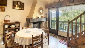 A cozy dining area with a round table, chairs, a fireplace, and a view of the outdoors. - Cozy duplex 35m² near Combloux center, facing Mont Blanc (Combloux)