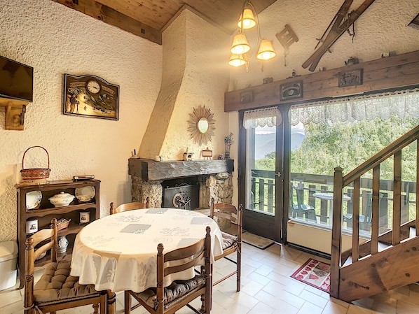 A cozy dining area with a round table, chairs, a fireplace, and a view of the outdoors.