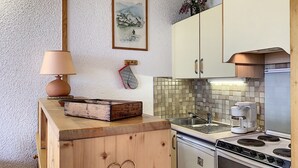 A compact kitchen with a wooden countertop, a stove, a sink, and a coffee maker.