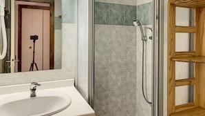 A bathroom with a shower, a sink, and a mirror.