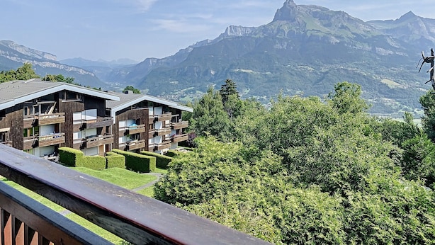 A mountain lodge with multiple balconies overlooking a valley and mountains.