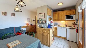 Une cuisine compacte avec des meubles en bois, un four à micro-ondes et un évier. Il y a également un coin repas avec une table et des chaises.