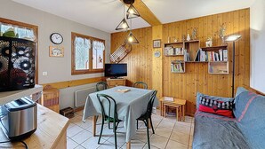 Une pièce confortable avec une table à manger, des chaises, un canapé, un téléviseur et une bibliothèque.