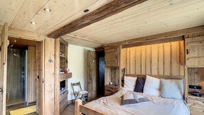 A wooden bedroom with a bed, a chair, and built-in wooden cabinets.