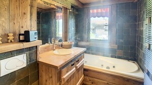 A wooden cabin bathroom with a bathtub, wooden vanity, and a mirror.