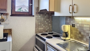 A compact kitchen with a stove, oven, and a coffee maker. - Charming 2-room apartment in Combloux center with balcony (Combloux)