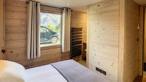 A wooden-paneled room with a bed, a window with curtains, and a view of a car outside.
