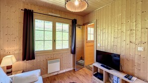 Una habitación con paneles de madera, un televisor, un sofá y una ventana con cortinas.